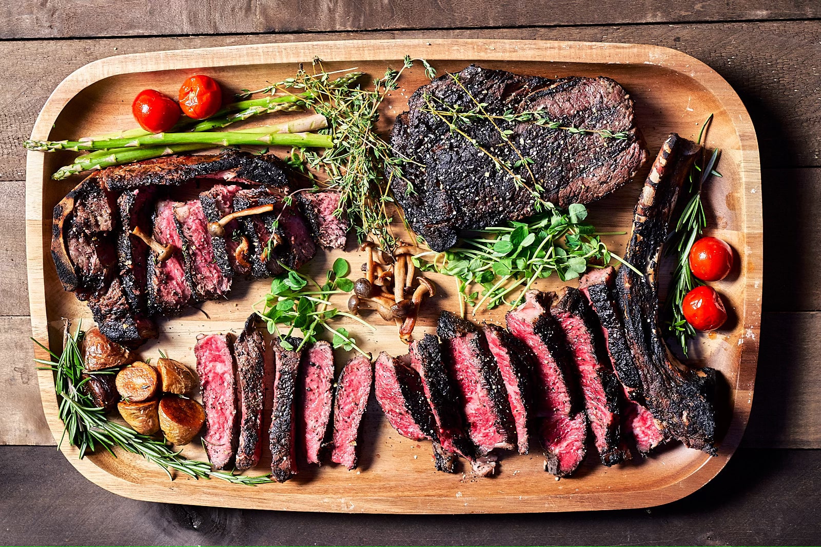 Assortment of steaks beautifully cooked, cut and plated with garnishes and aromatics around them