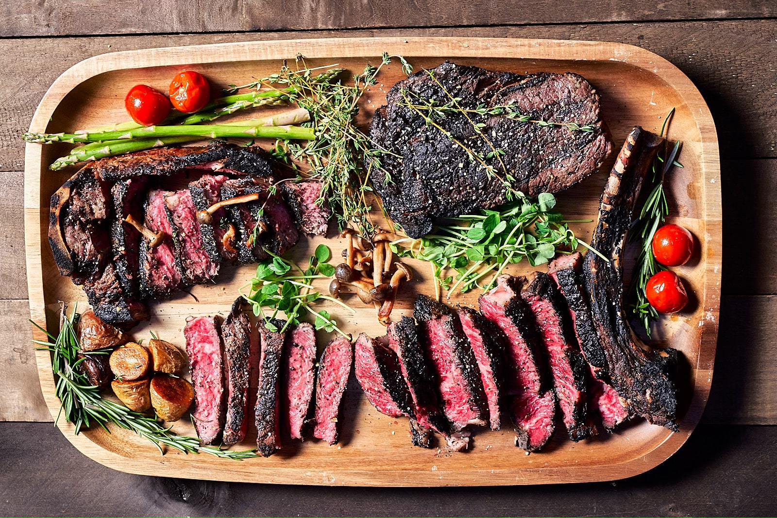 Assortment of steaks beautifully cooked, cut and plated with garnishes and aromatics around them