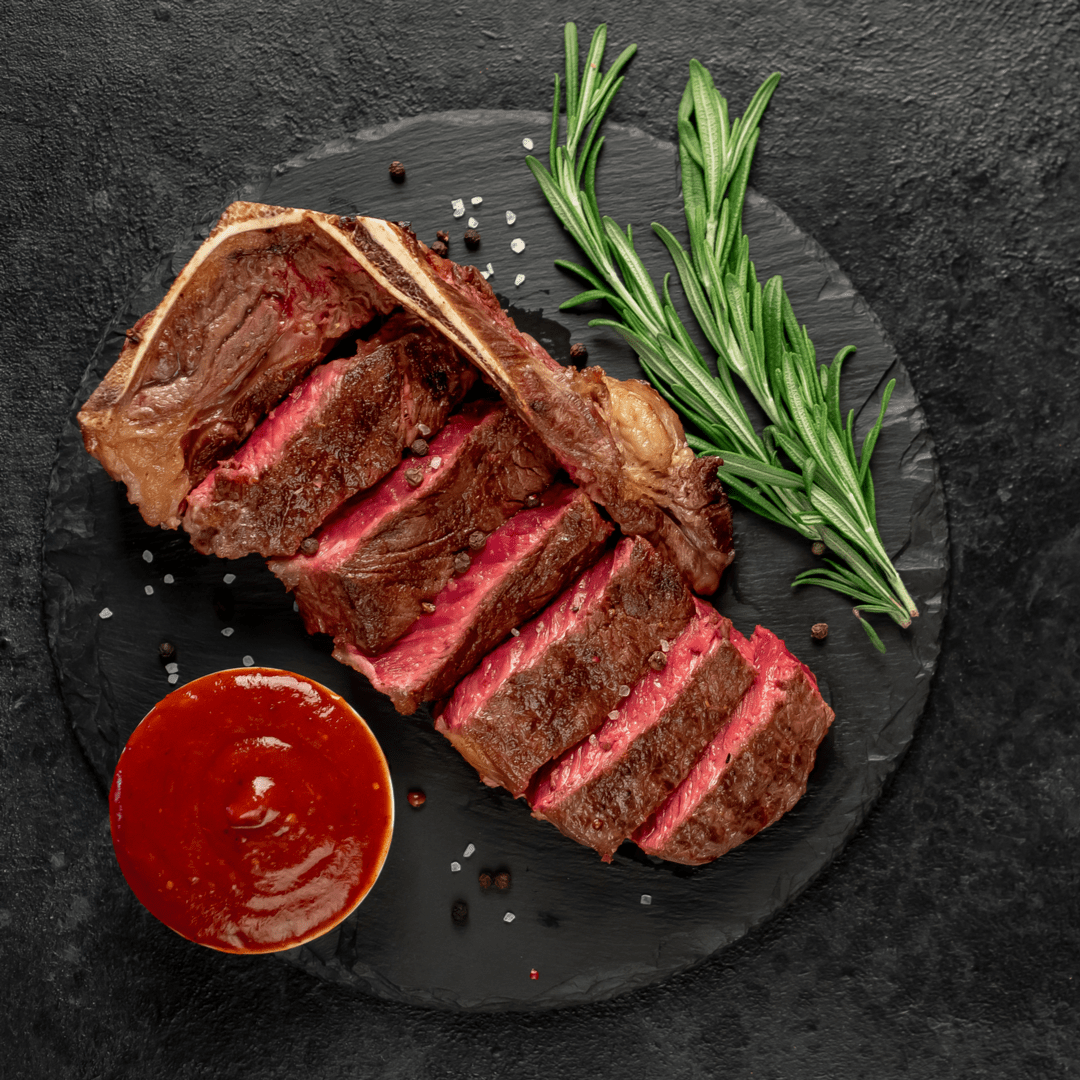 Perfectly cooked Bone-In New York strip with homemade steak sauce and rosemary on the side