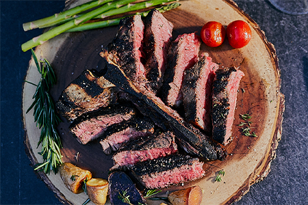 Juicy Porterhouse, grilled to perfection and plated beautifully with rosemary, asparagus, cherry tomatoes and potatoes.