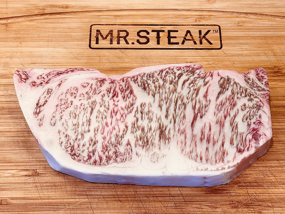 Beautifully marbled Japanese wagyu New York Strip on a Mr. Steak cutting board