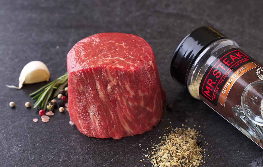 Juicy beef tenderloin steak beside Mr. Steak's "Super Blend" seasoning, garlic, and rosemary