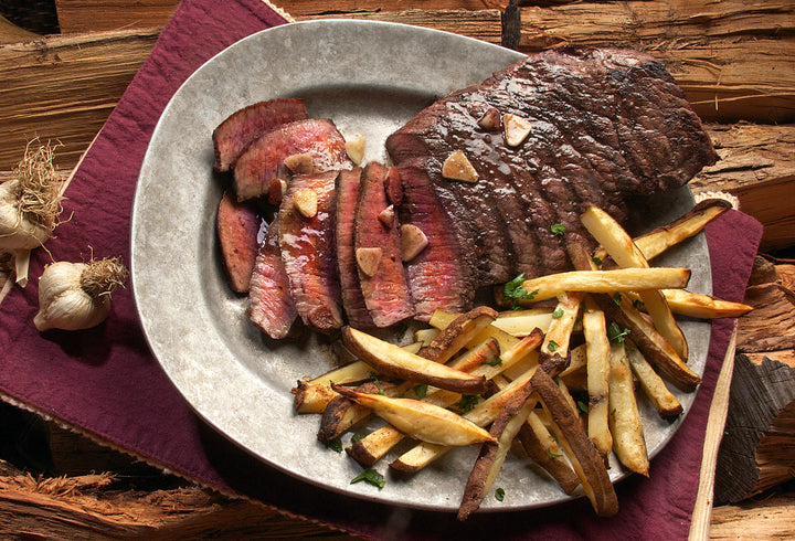 Beautifully cooked and plated flat iron steak with a side of fries