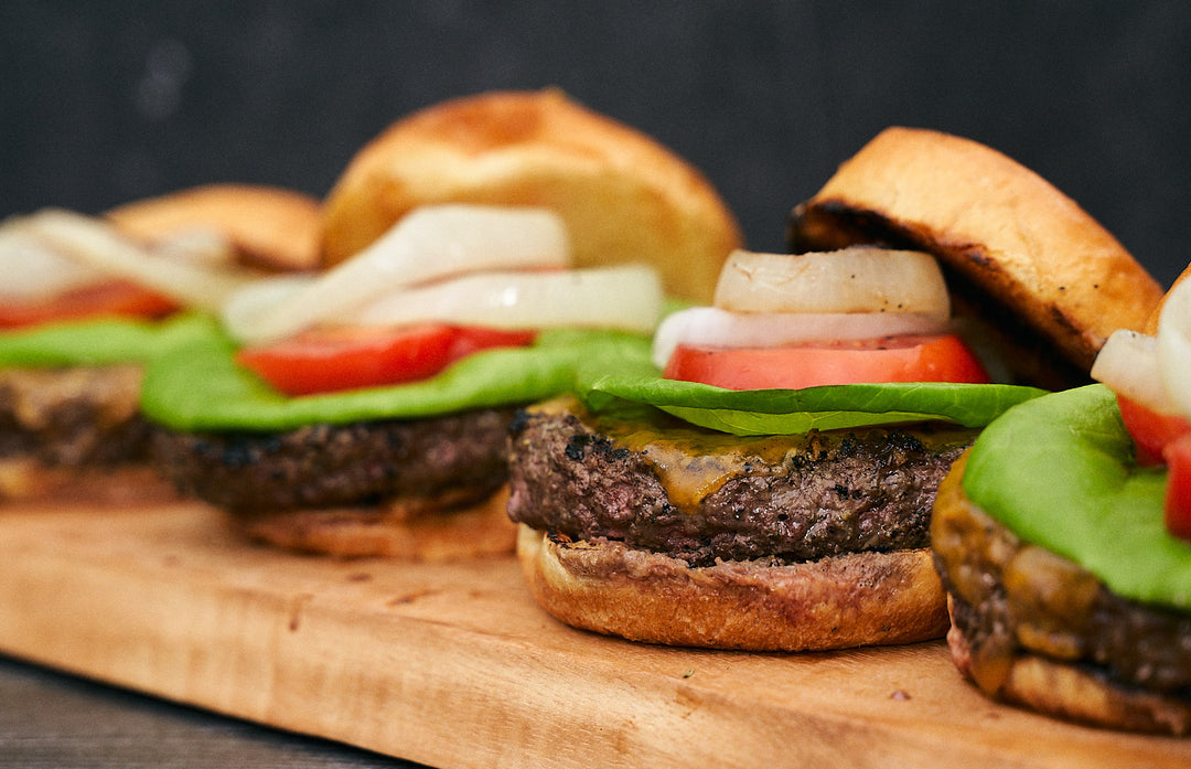 4 juicy steak burgers with lettuce, tomato, and onions on toasted buns