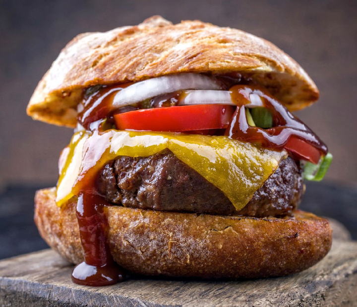 Juicy cheeseburger dripping with bbq sauce, topped with tomato, onion, and lettuce